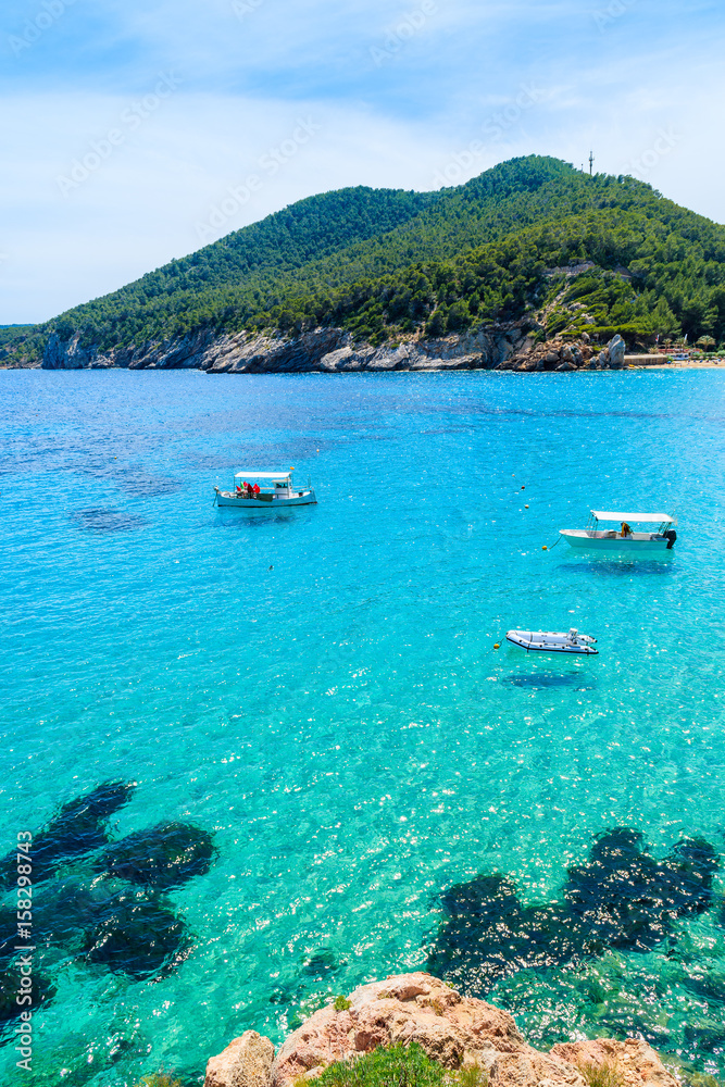 Fishing boats on turquoise sea water in Cala San Vicente bay, Ibiza island, Spain
