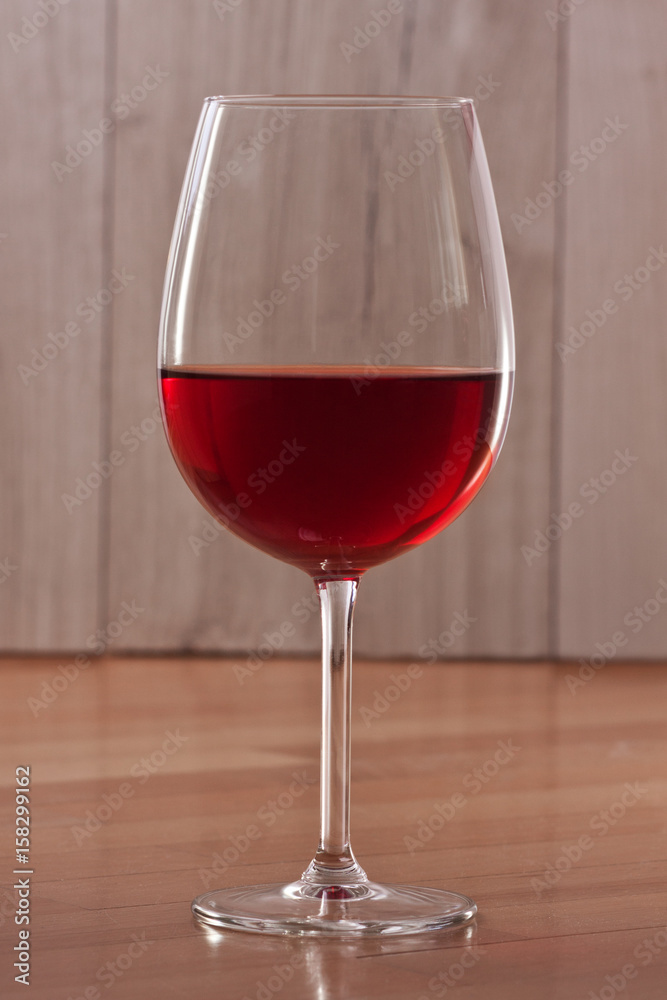 Red wine in a glass. A single glass. Colorful background. Wine-making. Reflection from a glossy surface.

