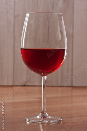 Red wine in a glass. A single glass. Colorful background. Wine-making. Reflection from a glossy surface. 