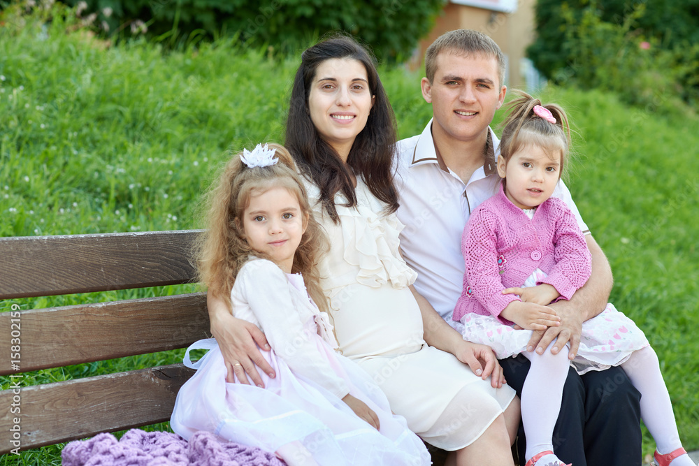 happy family in summer city park outdoor, pregnant woman, parent and children, bright sunny day and green grass, beautiful people portrait happy family in summer city park outdoor, pregnant woman, parent and children, bright sunny day and green grass, beautiful people portrait