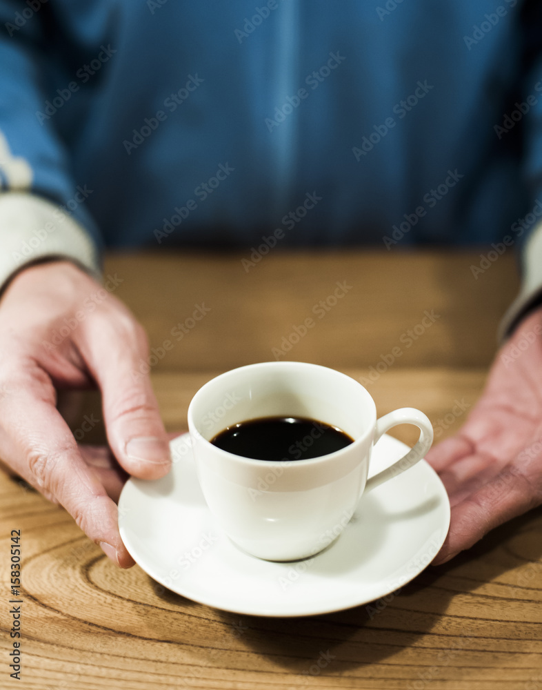 Close -up of man's hand holding coffee cup on table Close -up of man's hand holding coffee cup on table