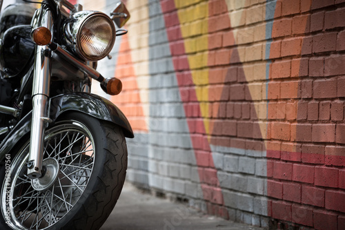 Fototapeta Closeup of motorcycle's wheel on bright colorful graffiti background