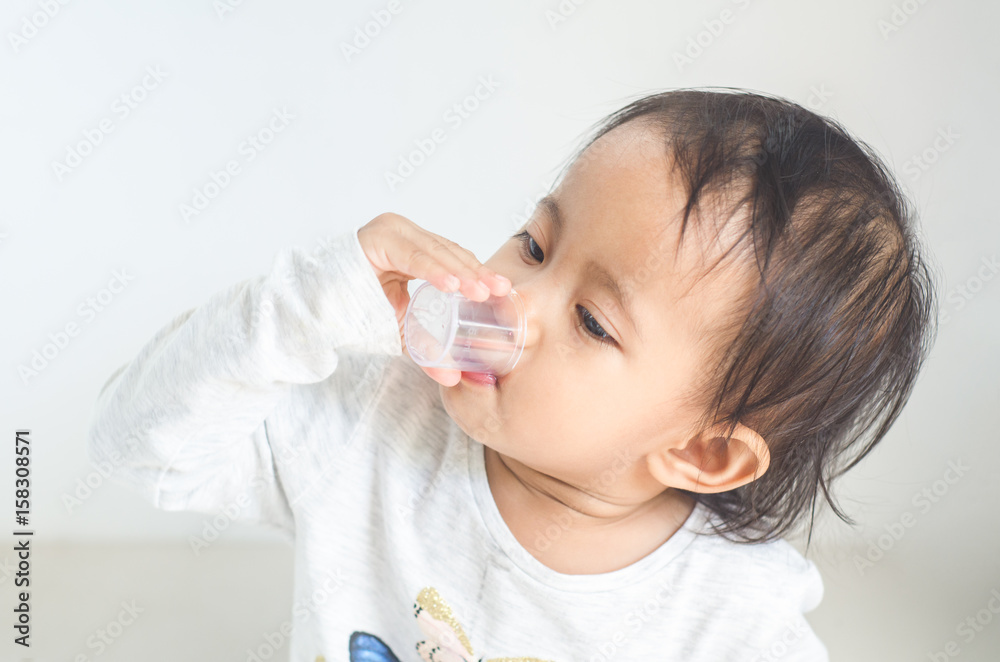 Asian little girl takes medicine syrup by herself Asian little girl takes medicine syrup by herself