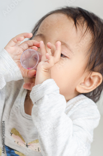 Asian little girl takes medicine syrup by herself
