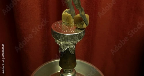 Shisha bowl with craft tobacco and red coil with hookah smoke background. Large hookah for Smoking tobacco made of metal. Red interior photo