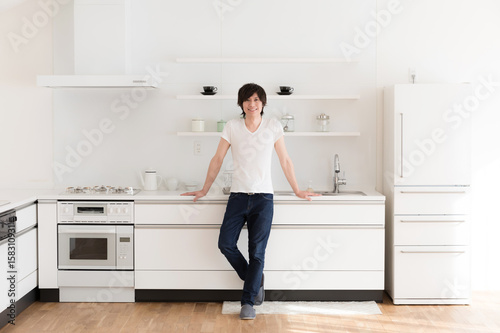 young asian man relaxing in kitchen