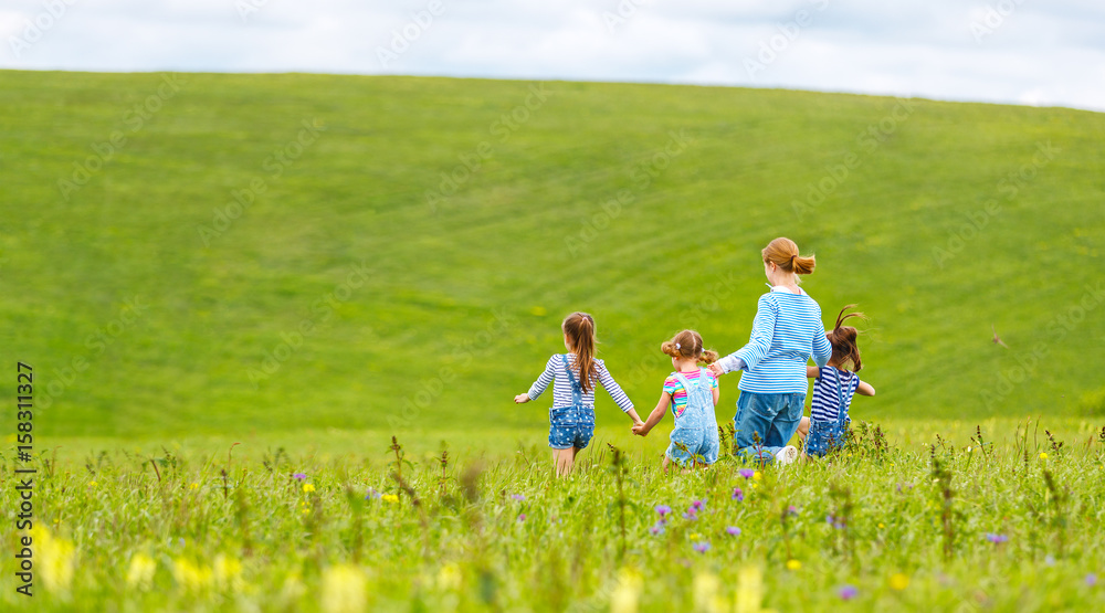 Fototapeta premium Happy family mother and children daughter girls laughing and running on meadow in summer
