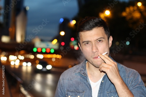Man smoking a cigarette in the city streets at night