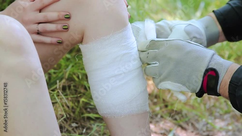 Young man wrapping girls leg with bandage closeup