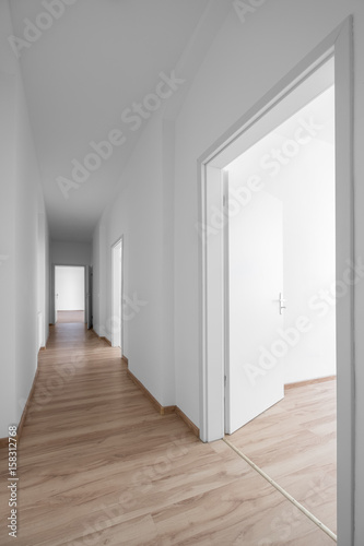 empty corridor, white walls and wooden floor - new apartment / new office