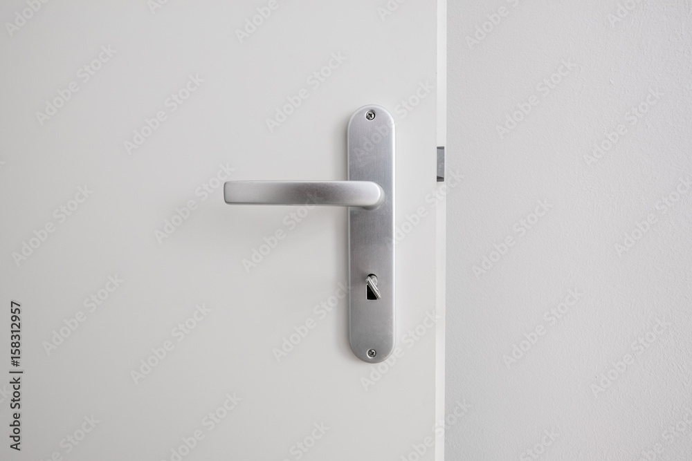 metal door handle with key on white door - obrazy, fototapety, plakaty 