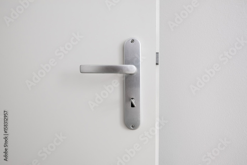 metal door handle with key on white door