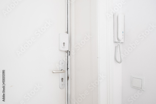 door handle , bar lock and interphone system on white apartment door