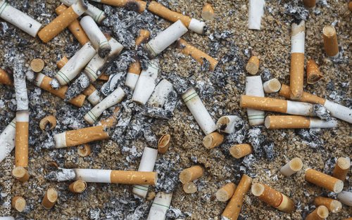Cigarette butts discarded on sand.