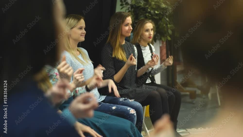 Young people are sitting in circle and applauding while having a meeting in the modern library Young people are sitting in circle and applauding while having a meeting in the modern library