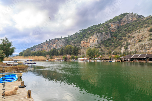 Dalyan canal and boats in the canal with rock graves of ancient greek kings
