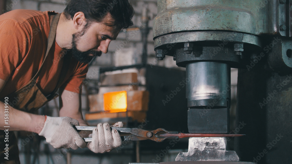 Molten metal is processed under pressure in the hands of a blacksmith Molten metal is processed under pressure in the hands of a blacksmith