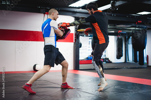 Two professionals fighters training together with punching pads at gym