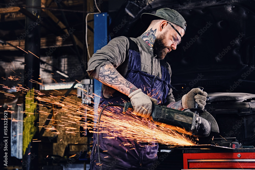 Mechanic cuts steel car part with an angle grinder. Mechanic cuts steel car part with an angle grinder.
