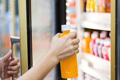 woman's hand open convenience store refrigerator shelves and pick product photo