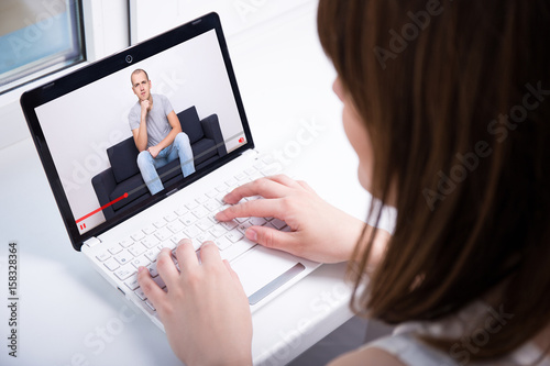 video blog concept - back view of young woman watching video on laptop