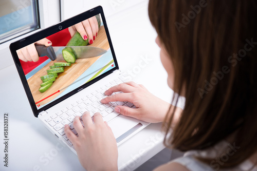 video blog concept - woman watching on laptop video about cooking