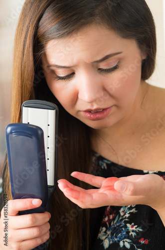 Beautiful young woman burned her hand using her ironing hair photo