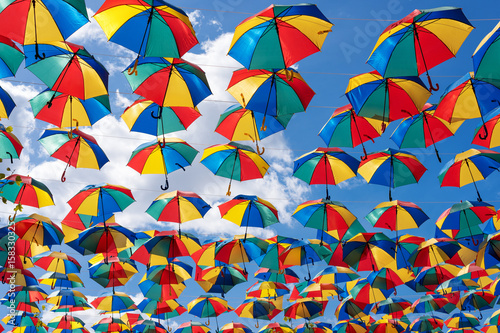 Colorful umbrellas background. Coloruful umbrellas urban street decoration. Hanging Multicoloured umbrellas over blue sky