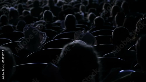 The audience applauded for a performance or presentation in the theater. Video from the back. Children and adults alike