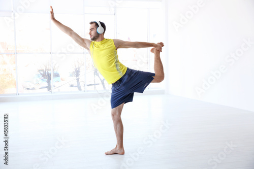 Man doing yoga and listenin...
