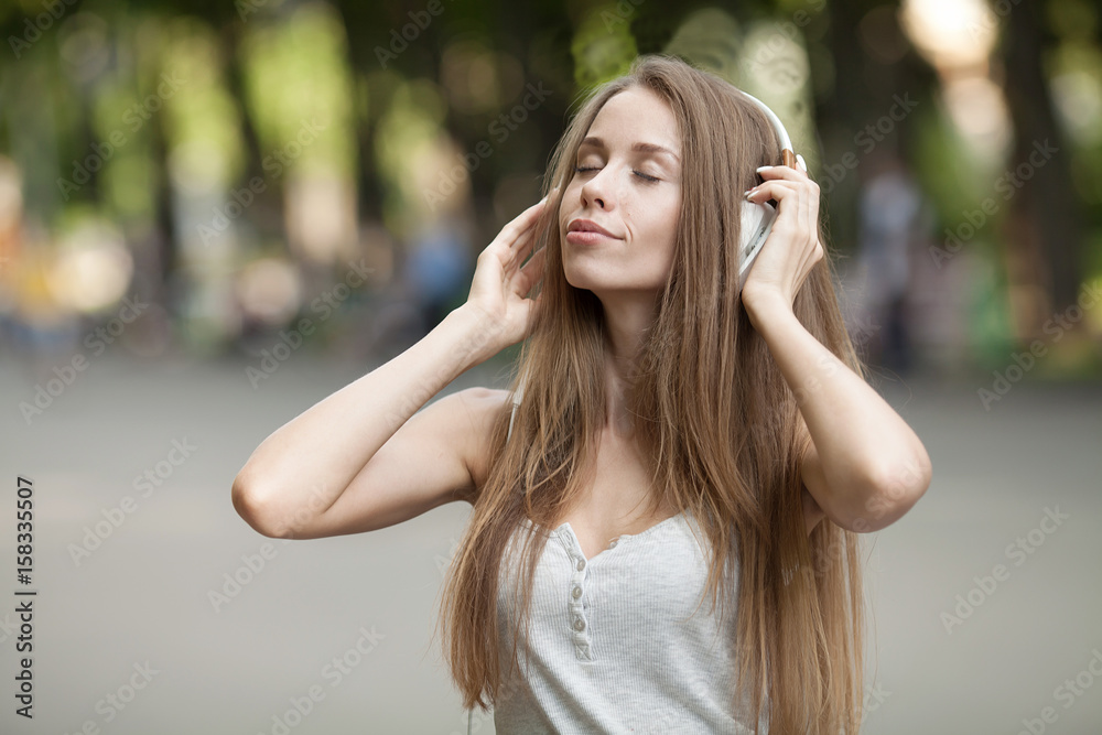 Pretty girl listening music with her headphones in the street