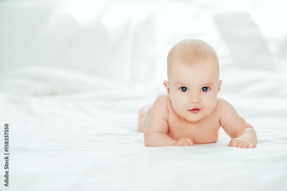 Adorable baby laying in white sunny bedroom. Newborn child relaxing in bed. Textile and bedding for kids. Family morning at home. Three month old infant child white soft blanket Adorable baby laying in white sunny bedroom. Newborn child relaxing in bed. Textile and bedding for kids. Family morning at home. Three month old infant child white soft blanket