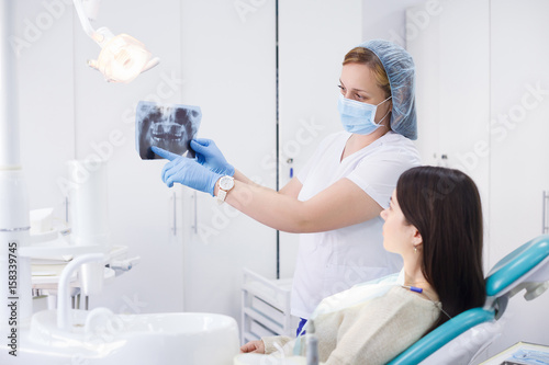 Photos Doctor talking with patient and showing a radiograph in stomatology clinic