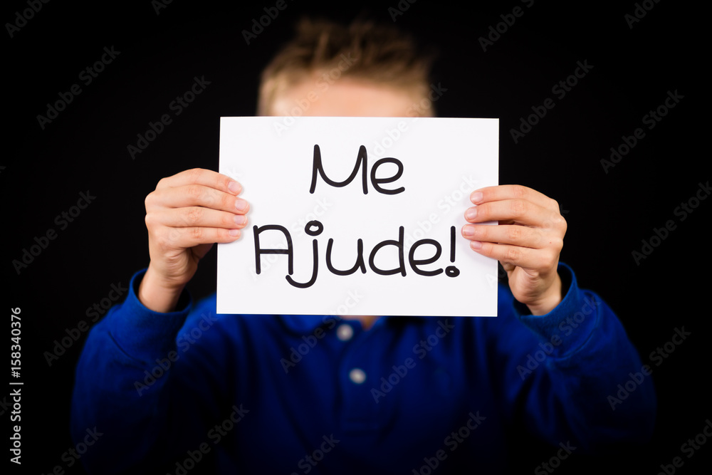 Child holding sign with Portuguese words Me Ajude - Help Me Child holding sign with Portuguese words Me Ajude - Help Me