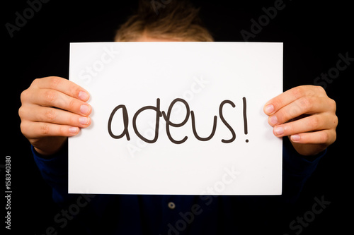 Child holding sign with Portuguese word Adeus - Goodbye photo