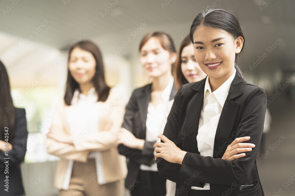Portrait of cheerful businesswoman with arms folded standing in front of colleagues Portrait of cheerful businesswoman with arms folded standing in front of colleagues