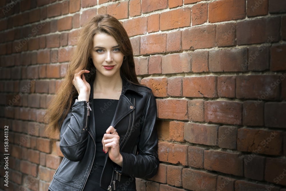 Girl with long hair near an old brick wall