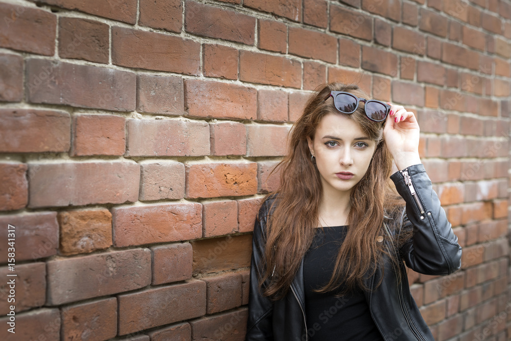 Girl with long hair near an old brick wall