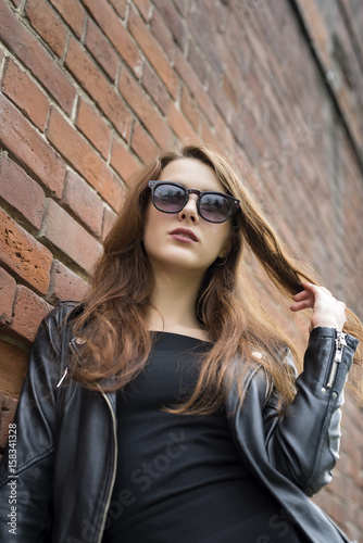 Girl with long hair near an old brick wall