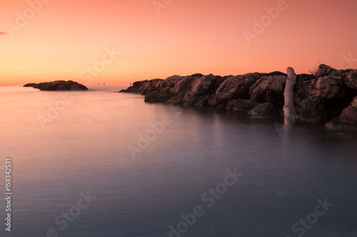 Orange sunset in front of the sea and stones in the water