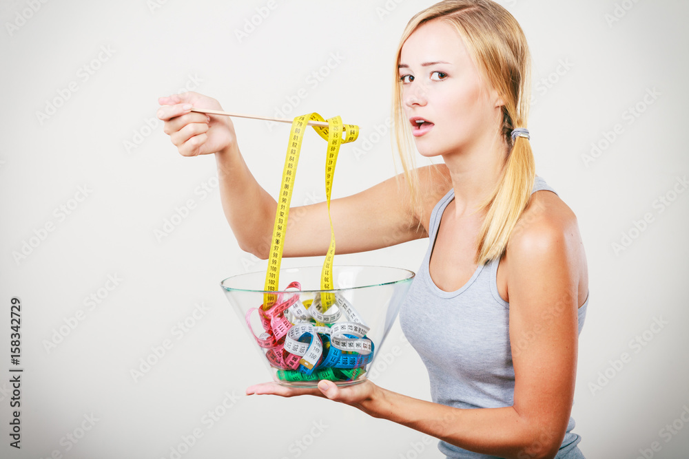 Diet. Girl with colorful measuring tapes in bowl Diet. Girl with colorful measuring tapes in bowl