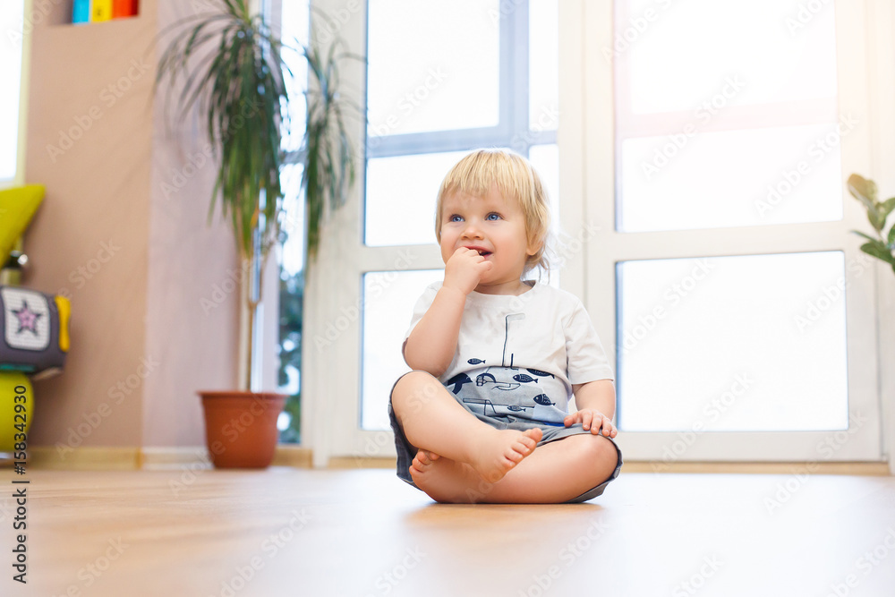 Cute smiling baby with teddy bear toy sitting at home in white room near window Cute smiling baby with teddy bear toy sitting at home in white room near window