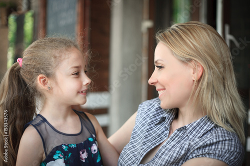 Portrait of a smiling young mother and daughter close-up outdoors.