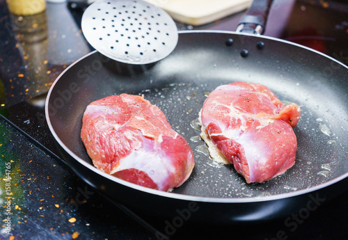 Two large pieces of meat in a frying pan.