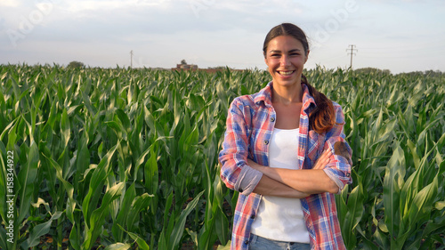 Obraz na plátně Beautiful girl (woman) farmer smiling, looking, checking cornfield, young tanned, green background