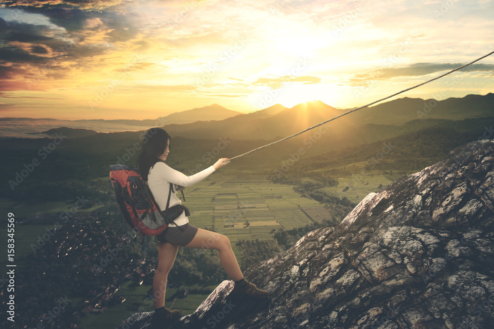 Asian female hiker climbing a steep mountain