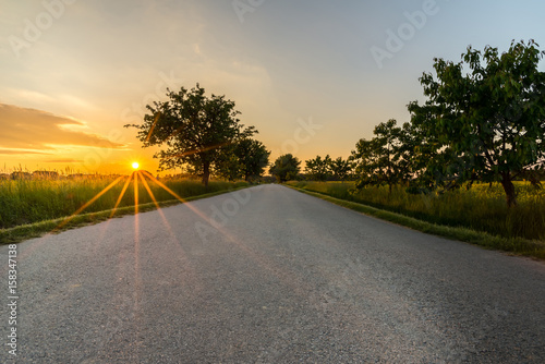 Sunset with long orange beams over the lone road