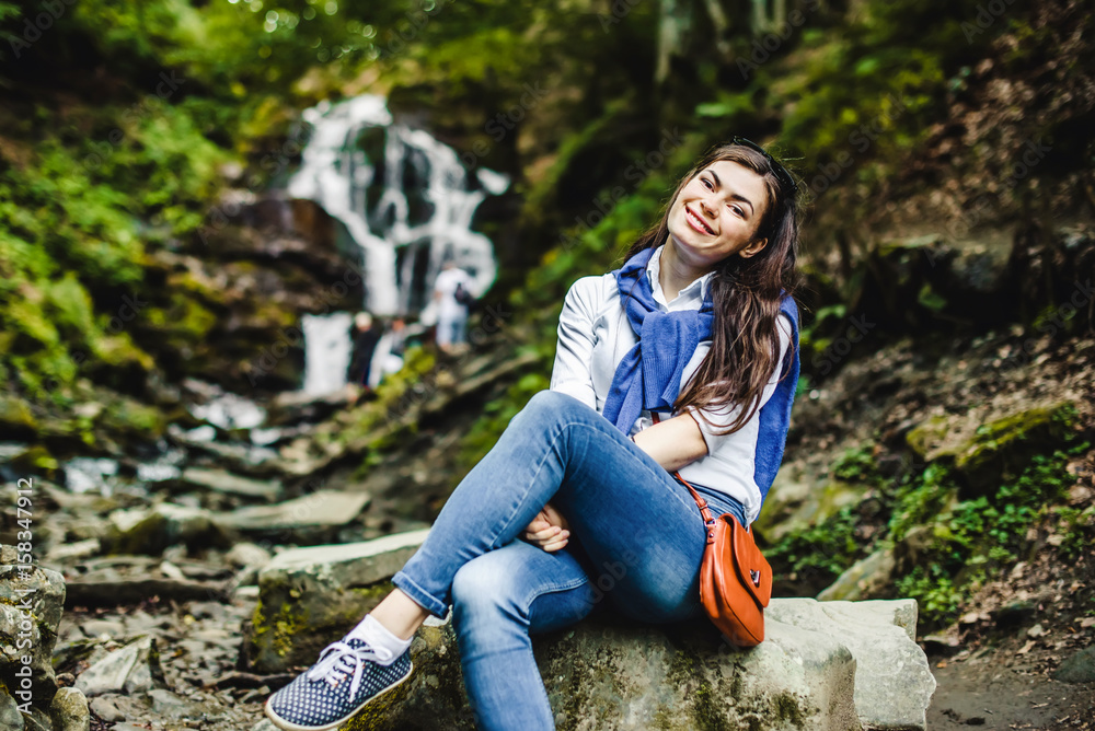 Happy young woman enjoying nature with waterfall in background Happy young woman enjoying nature with waterfall in background