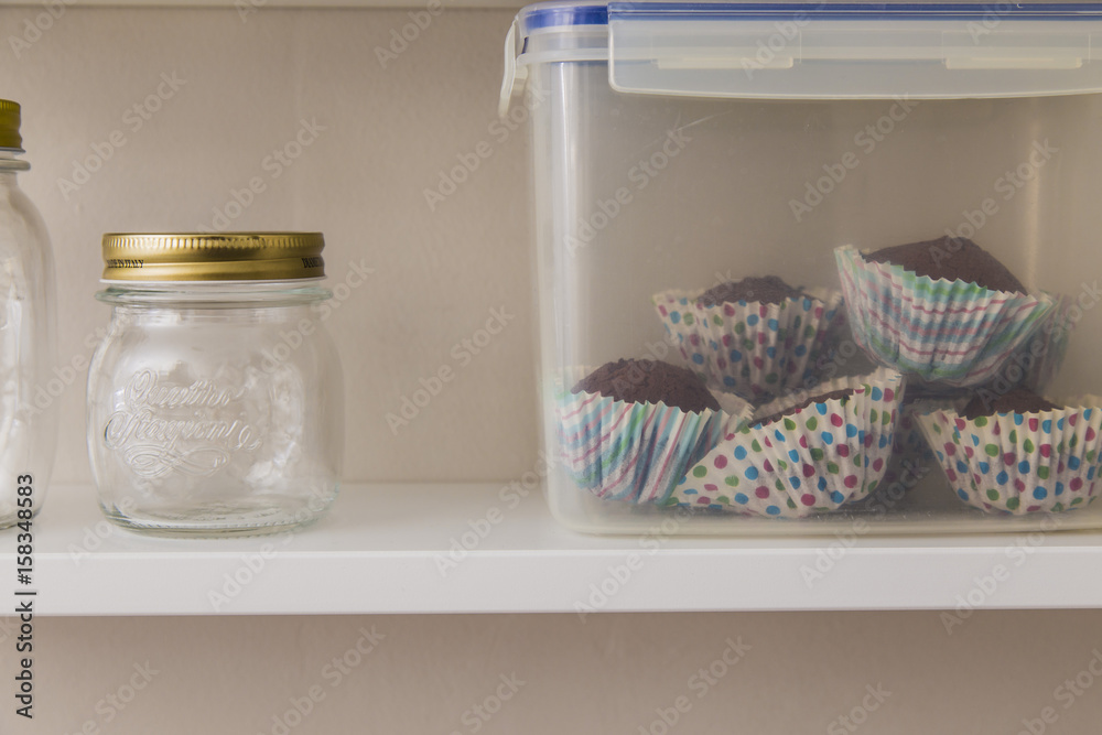 Glass pots and homemade muffins on a grey wall Glass pots and homemade muffins on a grey wall