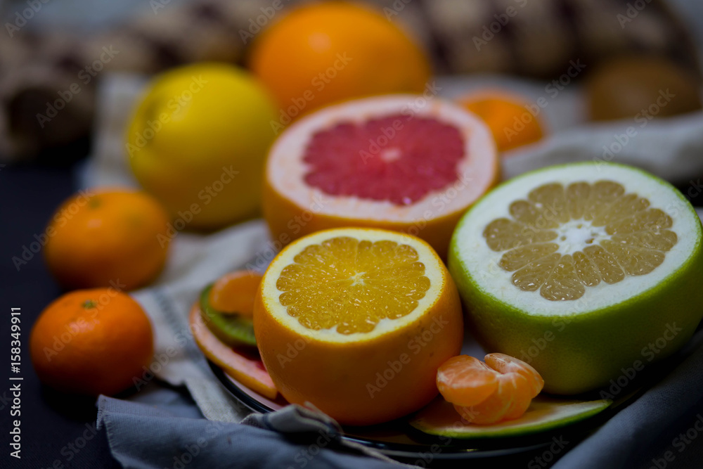 bright juicy citrus fruits in the dish and brown light beige kitchen towel in the kitchen, the festive table closeup bright juicy citrus fruits in the dish and brown light beige kitchen towel in the kitchen, the festive table closeup